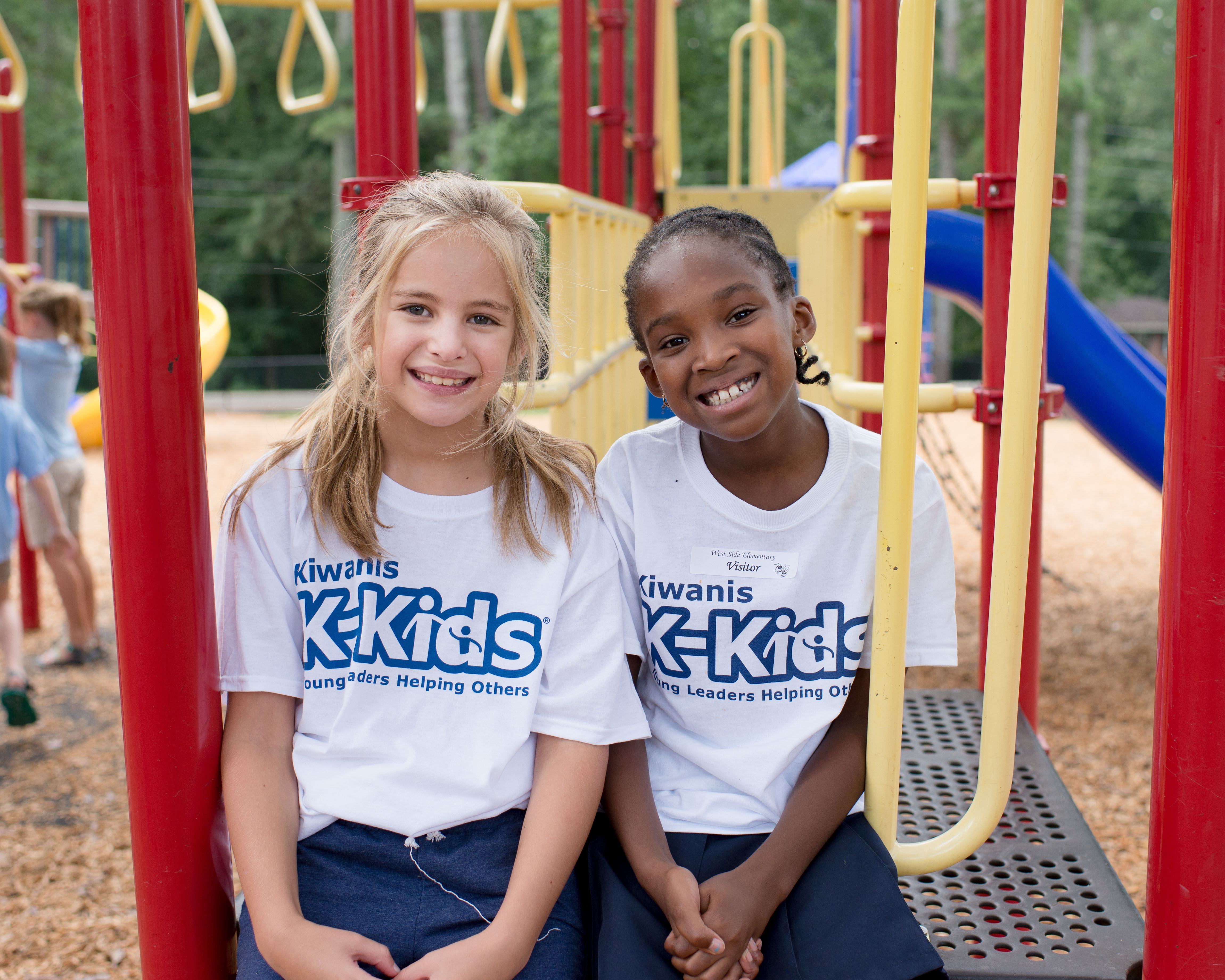 Two students on playground smiling in Kiwanis K-Kids t-shirts Two students on playground smiling in Kiwanis K-Kids t-shirts
