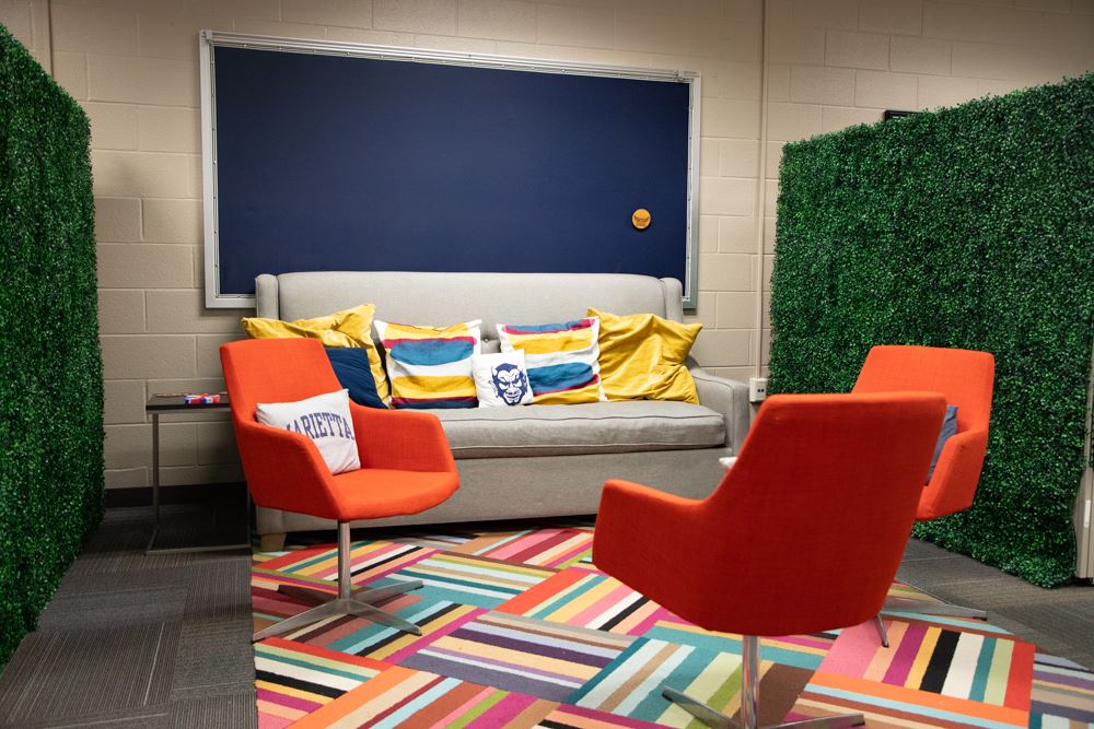 Room with bright orange chairs, couch, and striped rug