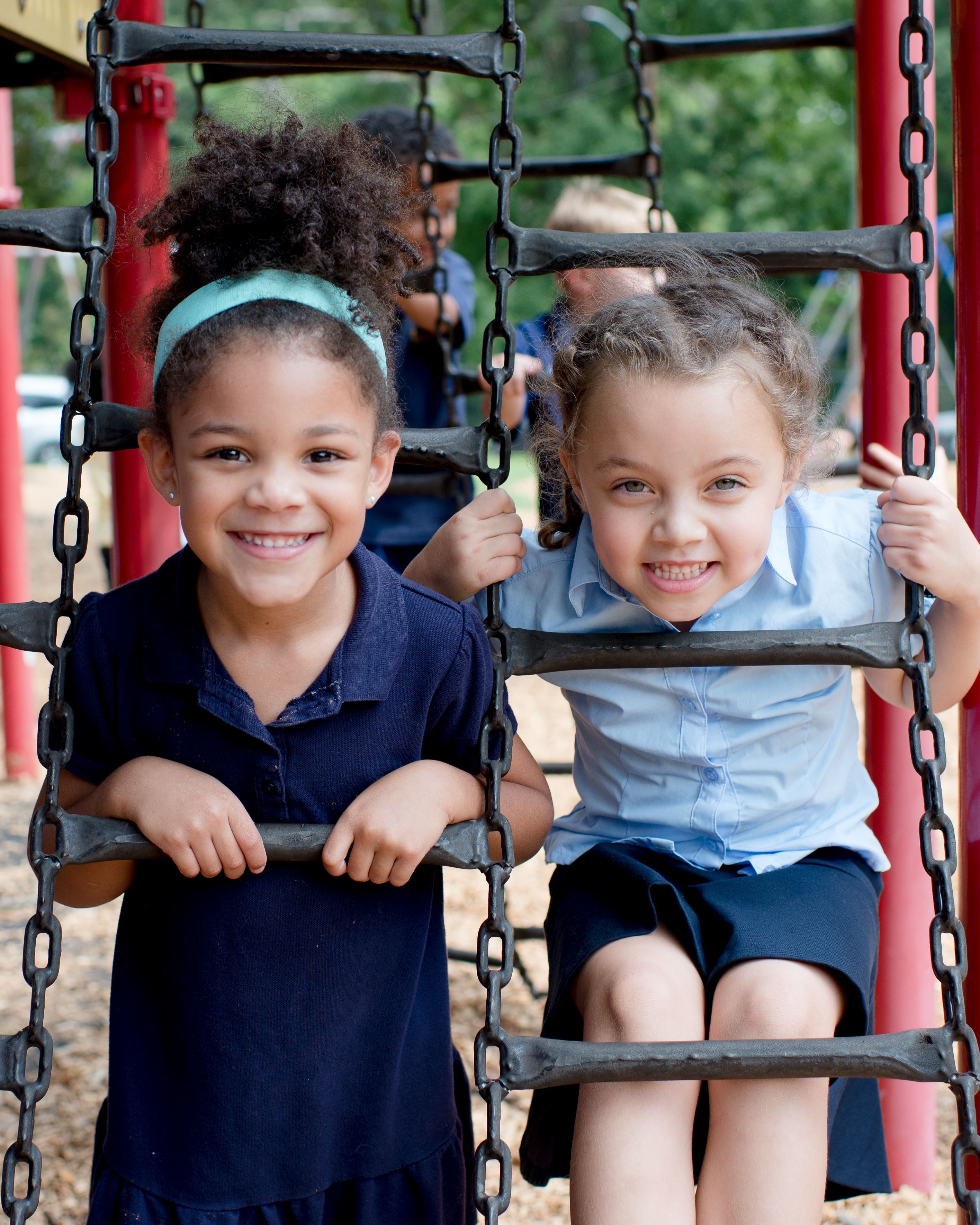 Two girls smiling on playground ladder Two girls smiling on playground ladder