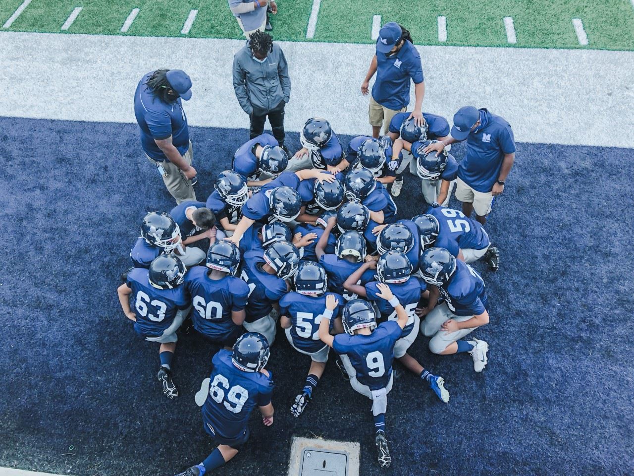 6th Grade Football Team 2018-19 huddles together in uniform