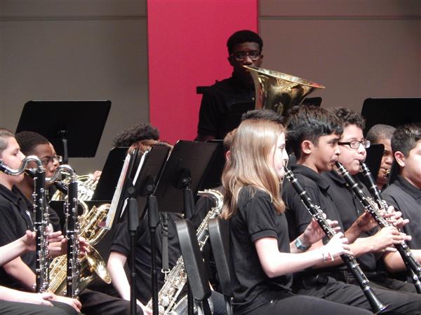 Students in black clothing performing with clarinets, oboes, saxophones, and tuba
