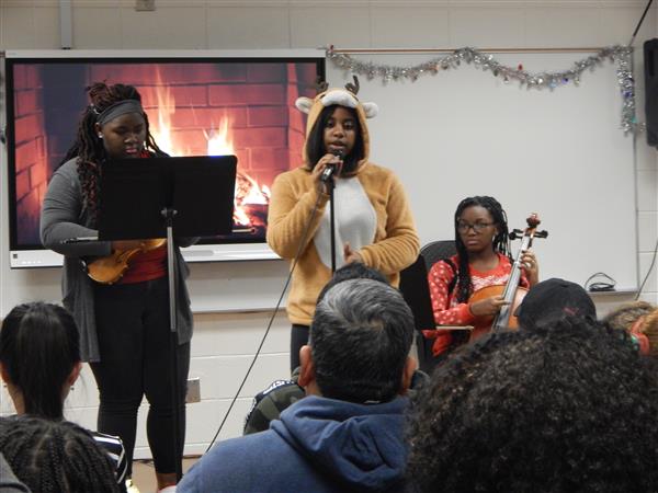 Group with student in reindeer costume sings in front of parents in classroom