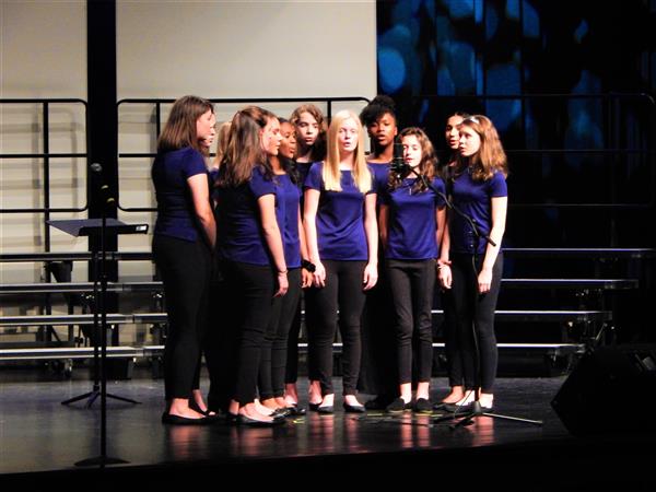 Cluster of female chorus students singing on stage