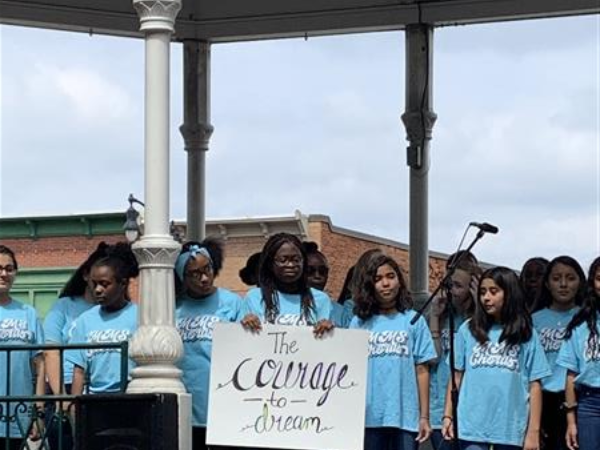 Close-up of chorus student holding sign that reads The Courage to Dream