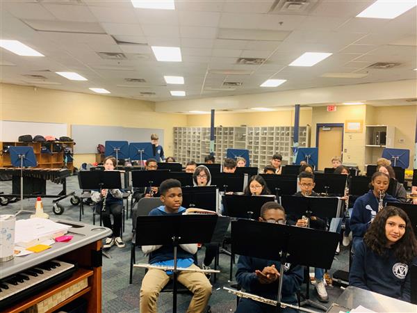 Wide shot of students seated behind music stands in band class