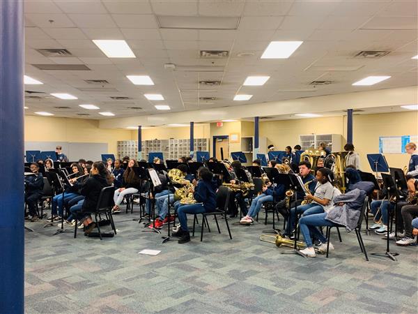 Wide shot of band students playing instruments in classroom