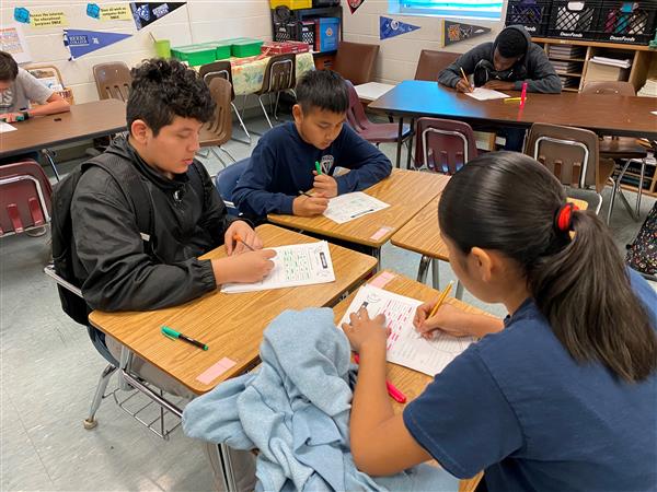 Three students working on papers at desks