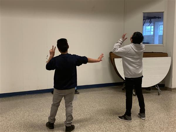 Two students facing blank wall and gesturing