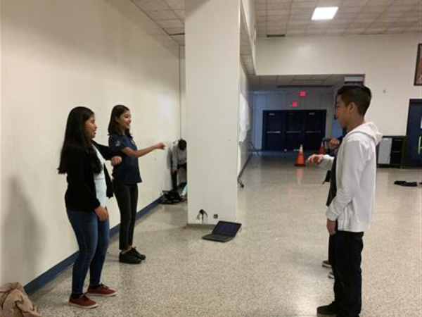 Two pairs of students facing one another doing expressive motions