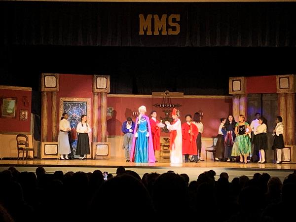 Wide shot of student play performance with cast in various costumes