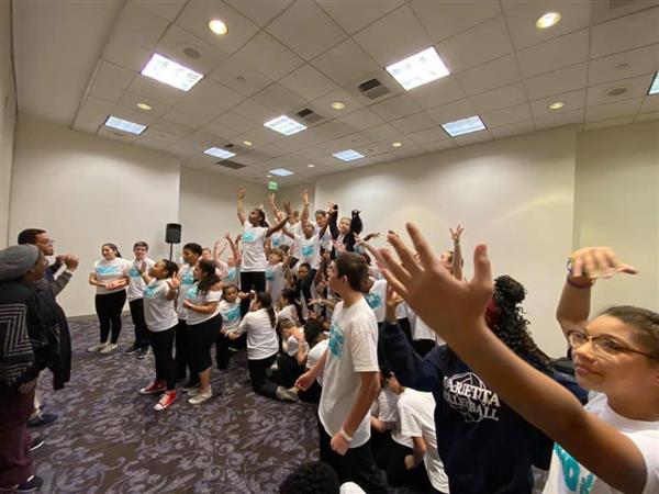 Group of students in classroom expressively gesturing with their arms