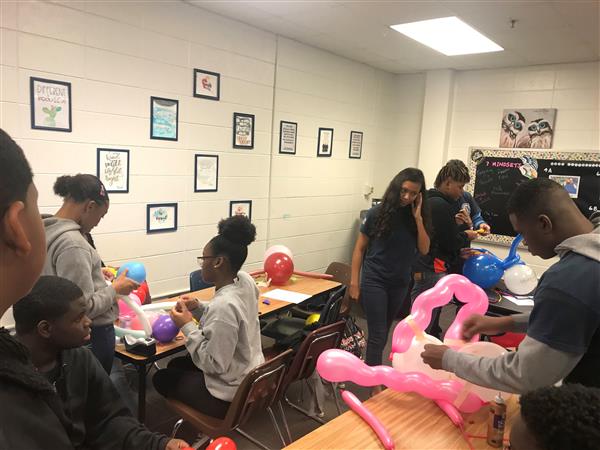 Students in classroom making art project with balloons