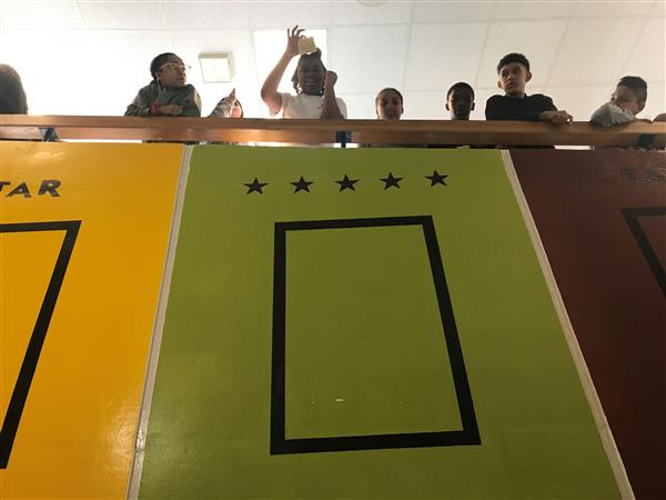 Students seen from below leaning over railing above colorful banners