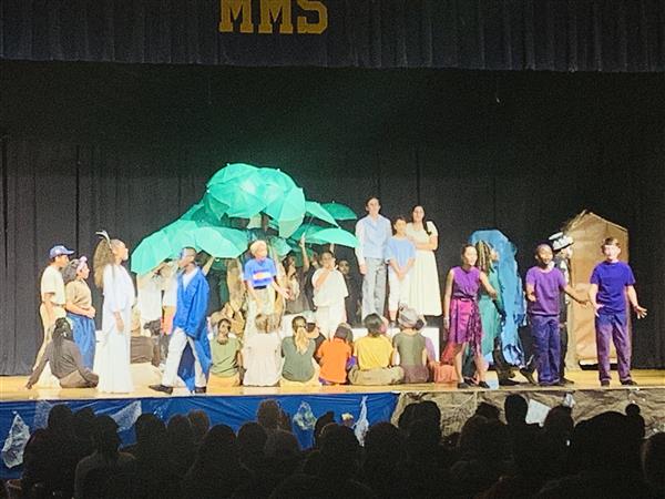 Students performers in a play on stage with island set and costumes