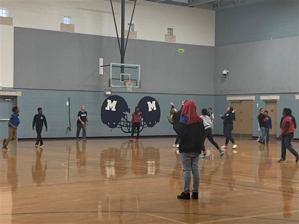 Students gathered playing a catching game in gymnasium