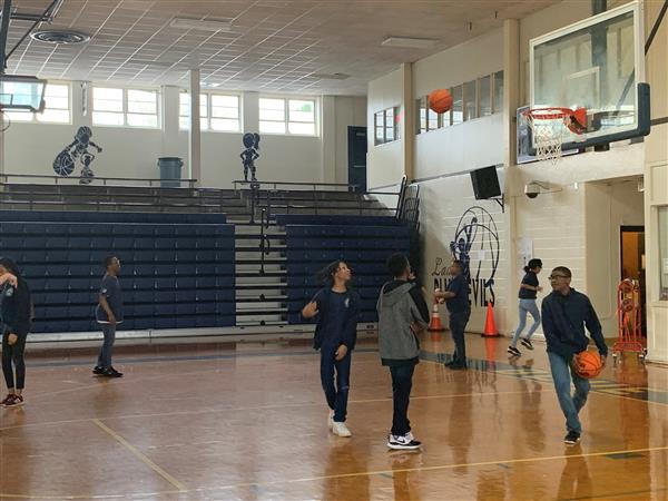 Cluster of students playing basketball in gymnasium
