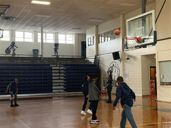 Students playing with basketball and football in gymnasium