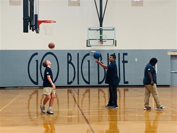 Three students playing ball in gymnasium