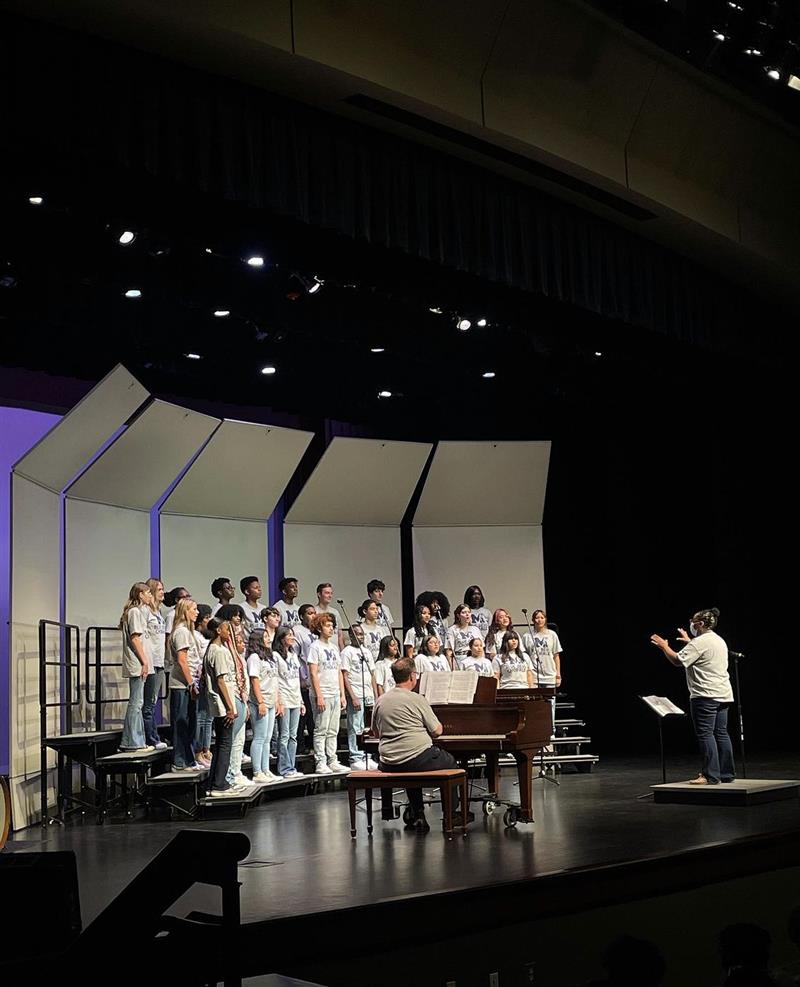 Chorus students stand on risers on stage during a performance