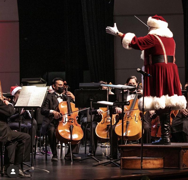 The conductor dressed as Santa conducts orchestra players in the middle of a performance
