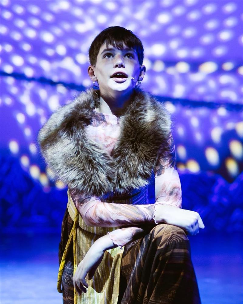 A student portrays Simba in a production of the Lion King looks up