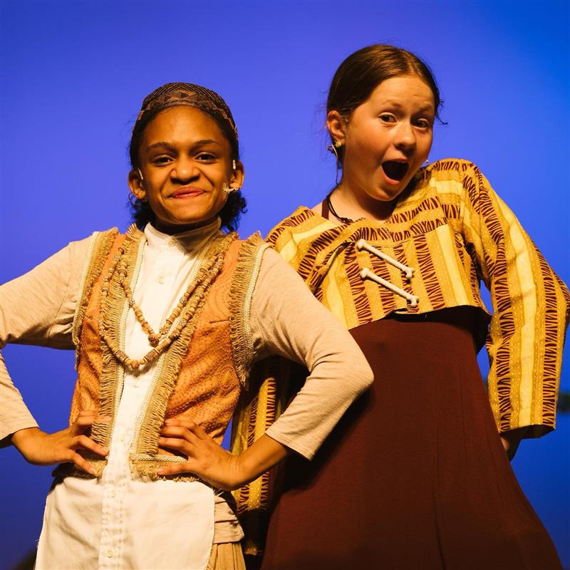 Students portraying Timon and Pumbaa strike a silly pose on stage at production of the Lion King