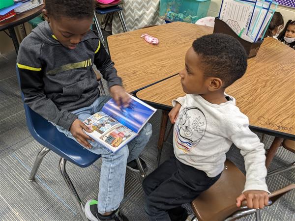 An older student reads aloud to a younger child