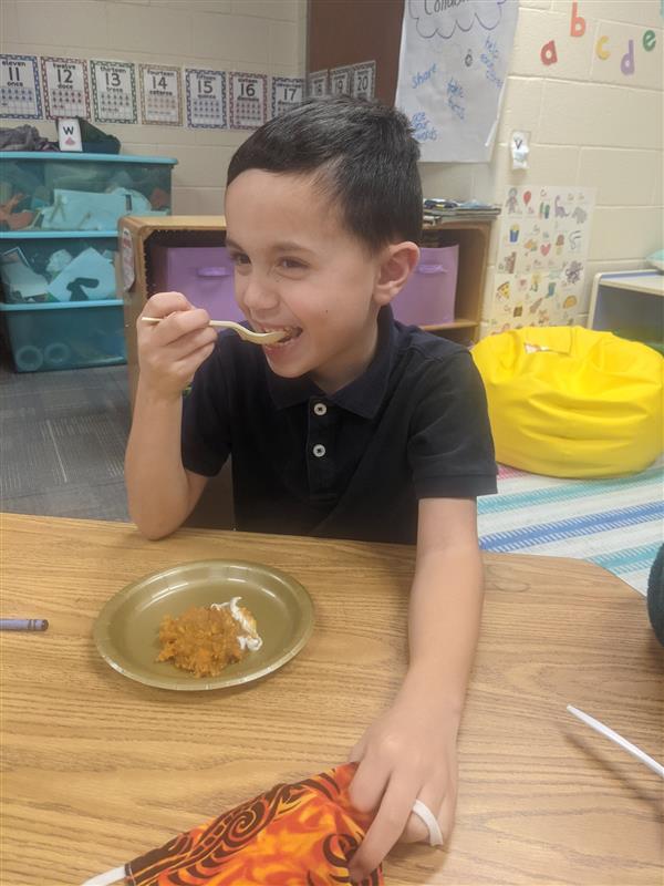 A student smiles as he samples a plate of food