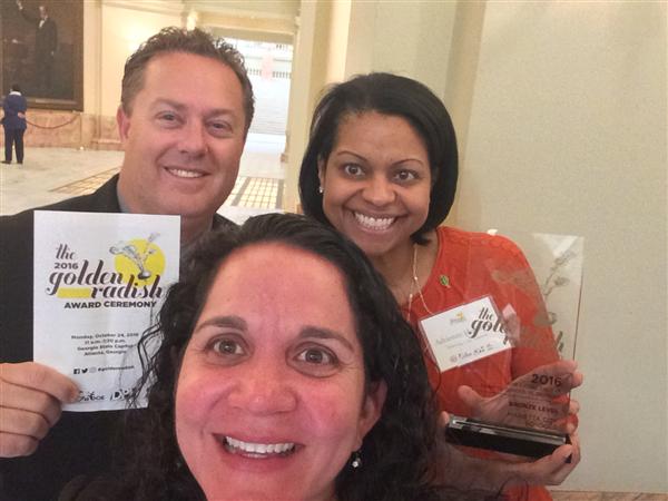 Three school nutrition employees holding trophy and certificate from the 2016 Golden Radish awards