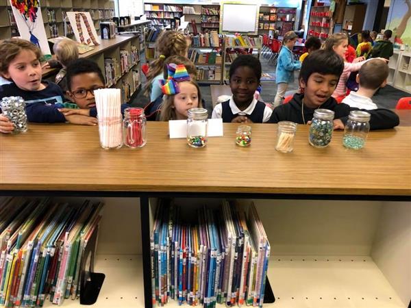 Students in library staring at jars filled with various objects