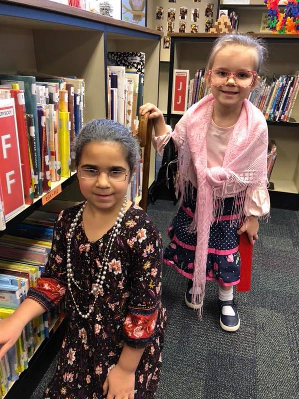 Two students in library in costume as elderly women