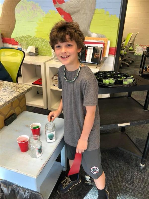 Student smiling while dropping an object in a glass jar