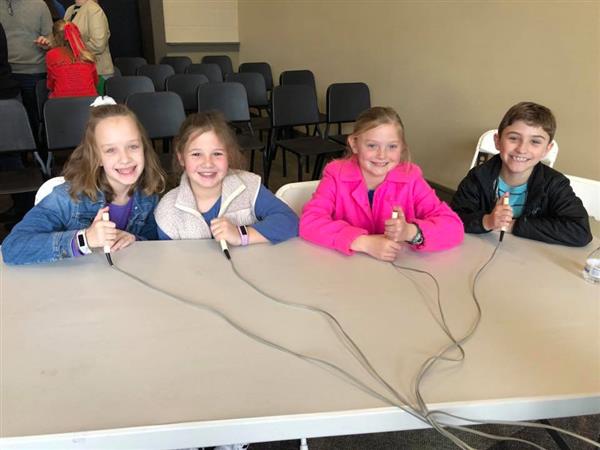Four students at table smiling and holding trivia buzzers