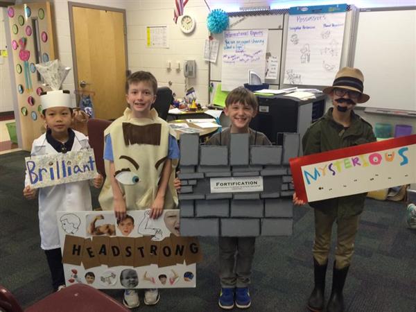 Students dressed in costumes representing words, explained by signs reading Brilliant, Headstrong, Fortification, and Mysterious