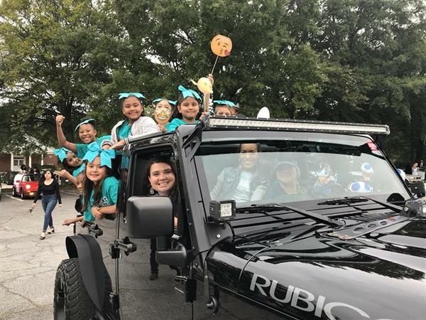 The Sawyer Road Cheer Team riding together in a Jeep during the MCS Homecoming Parade