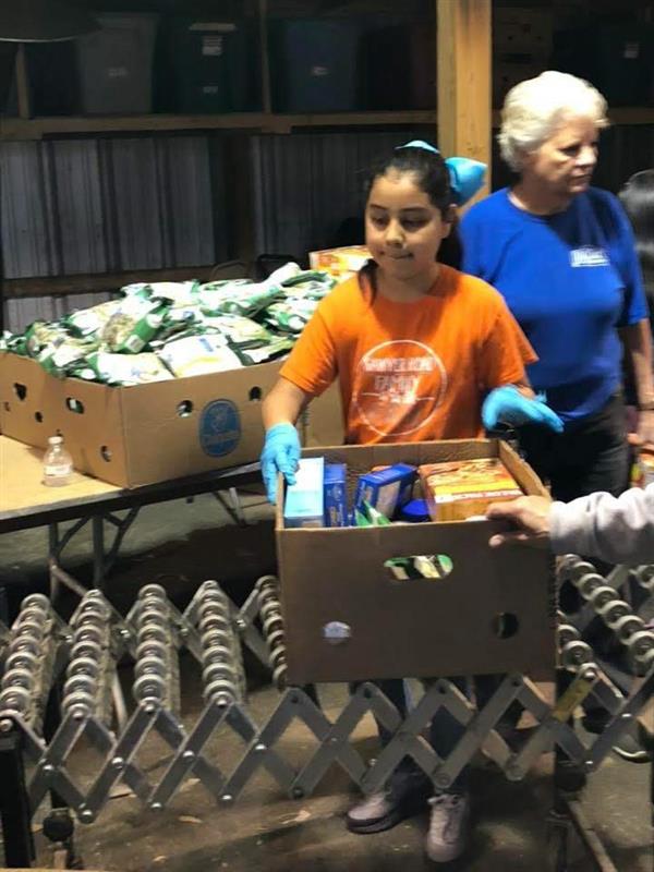 Sawyer Road student ambassador helping to pack a box of food for a local food pantry